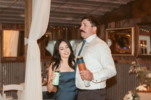 Couple enjoying drinks together at an event venue decorated with white drapes and wood paneling.