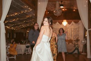 A wedding celebration in full swing with dancing guests under sparkling lights and white fabric decorations.