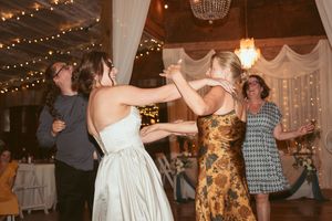 Lively dancing at a wedding reception with guests enjoying themselves under strings of fairy lights.