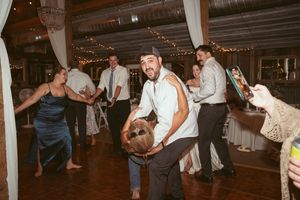 Energetic dancing at a wedding reception with guests showing off their moves on the wooden dance floor.