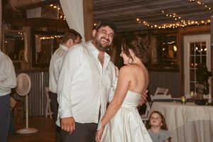 Wedding guests sharing joyful laughter and dancing during a reception in a rustic venue.