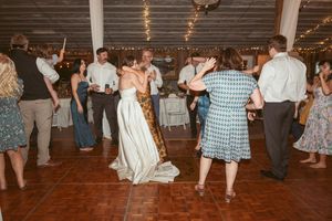 Wedding reception dance floor filled with guests enjoying themselves under string lights and rustic decor.