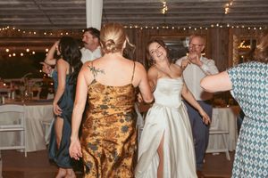 Wedding guests dancing and enjoying themselves at a rustic barn reception with string lights overhead.