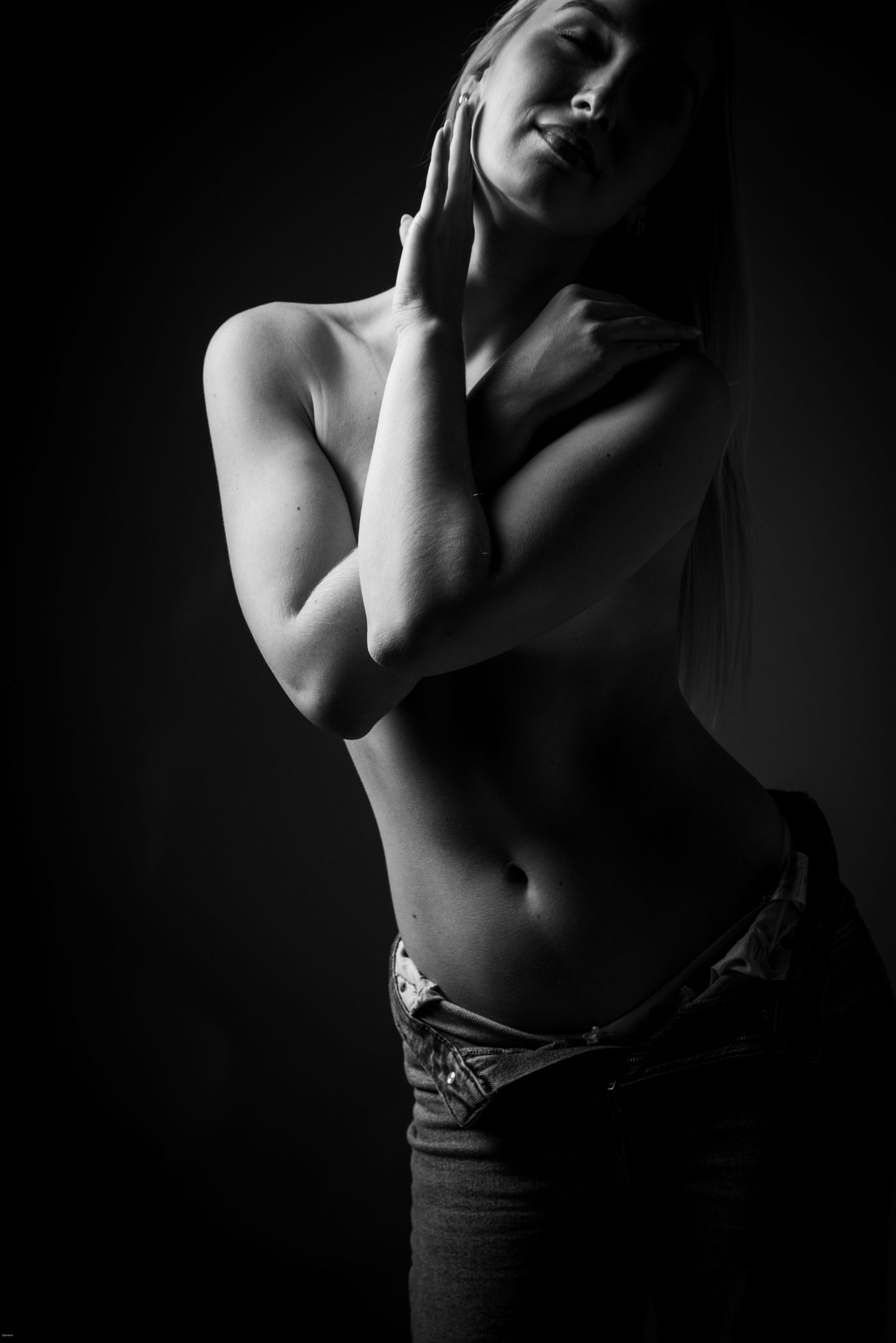 Künstlerisches Aktfoto einer Frau mit verschränkten Armen vor der Brust, noch in Jeans bekleidet – elegant, ausdrucksstark und reduziert.