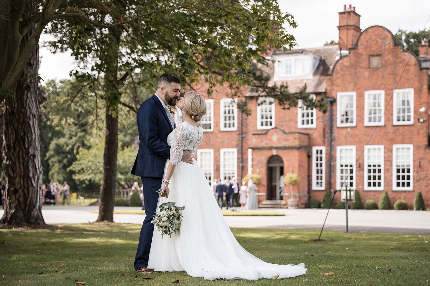 Elegant countryside wedding venue featuring brick buildings and manicured grounds.