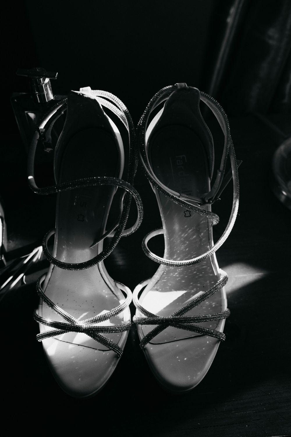 Dramatic black and white photo of bridal shoes with strappy details.