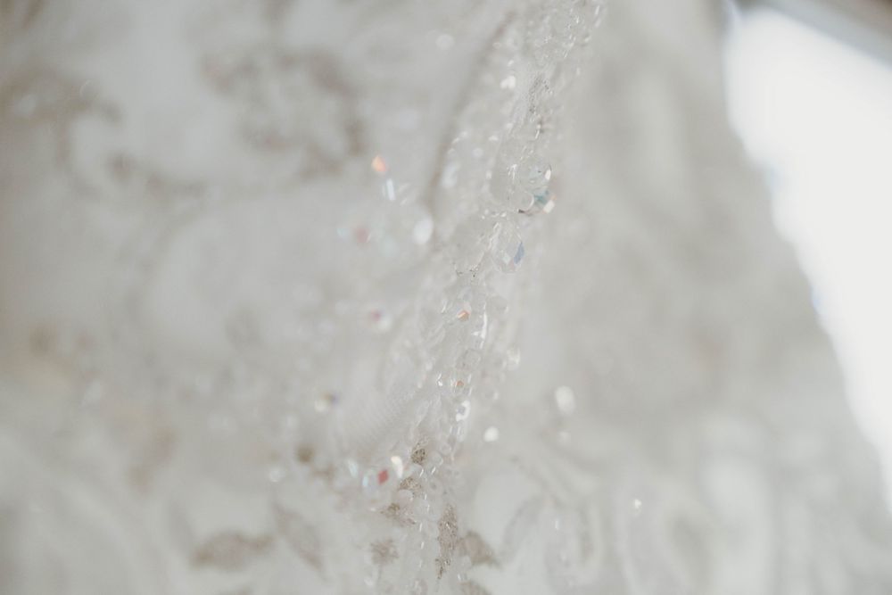Macro shot of delicate lace details on white fabric with sparkles.