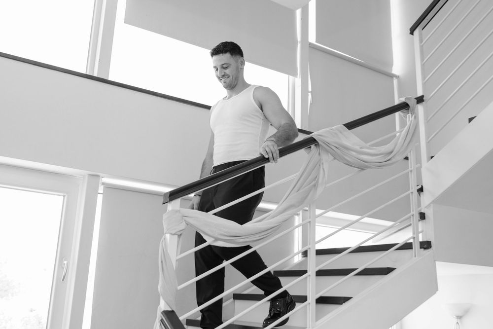 Person in casual white attire walking down modern white staircase.