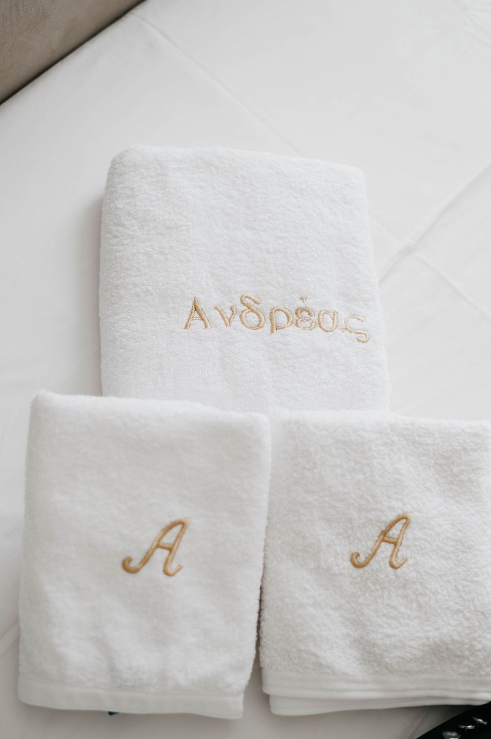 White monogrammed towels with gold embroidered letters and text.
