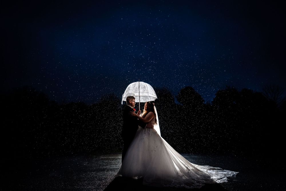 Dramatic nighttime silhouette of a couple in wedding attire against a dark sky.