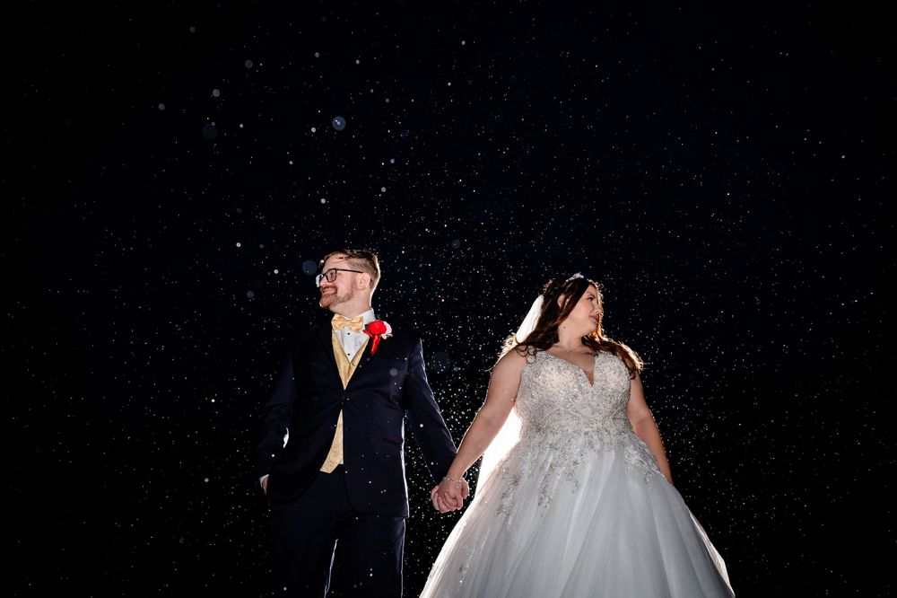 Wedding couple dancing under twinkling lights at an outdoor evening reception.