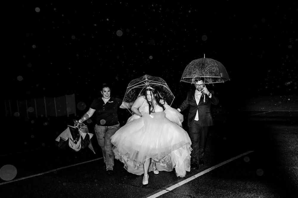 Wedding party celebrating in a boat on a dark lake with festive lighting.