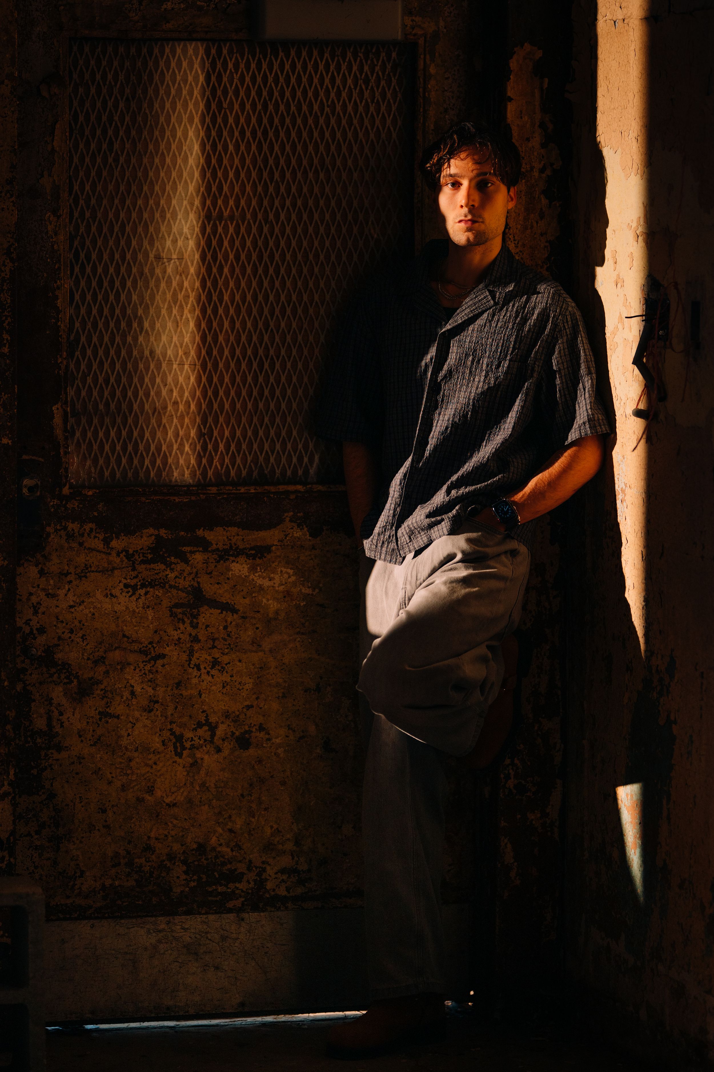 Moody portrait series in a dark industrial setting with brick walls and dramatic lighting.