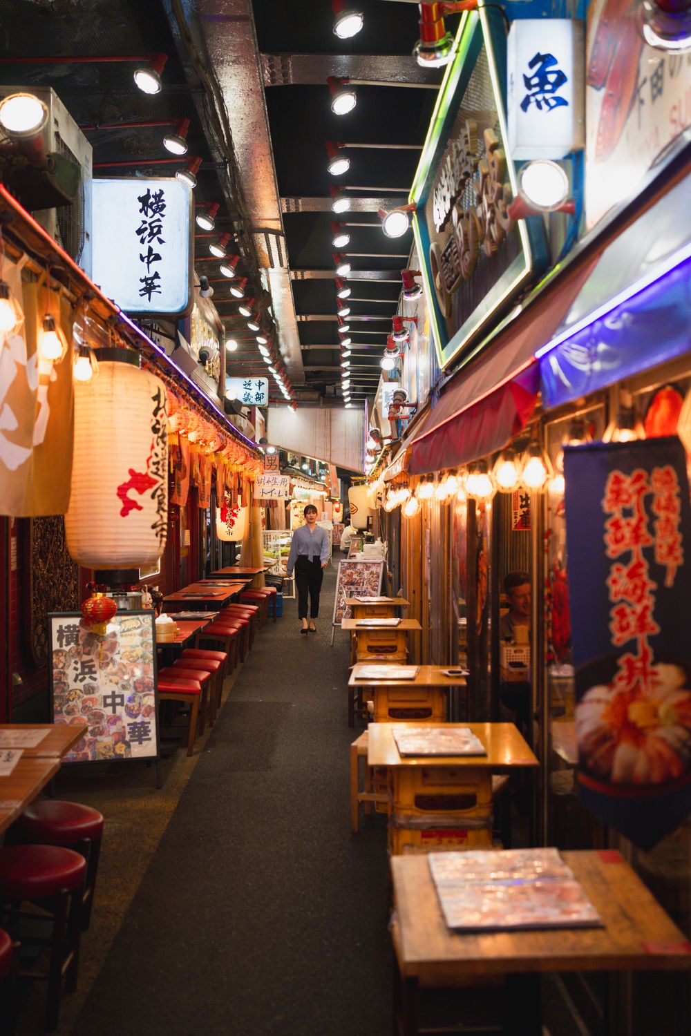 Traditional Japanese restaurant corridor with paper lanterns and wooden booths.