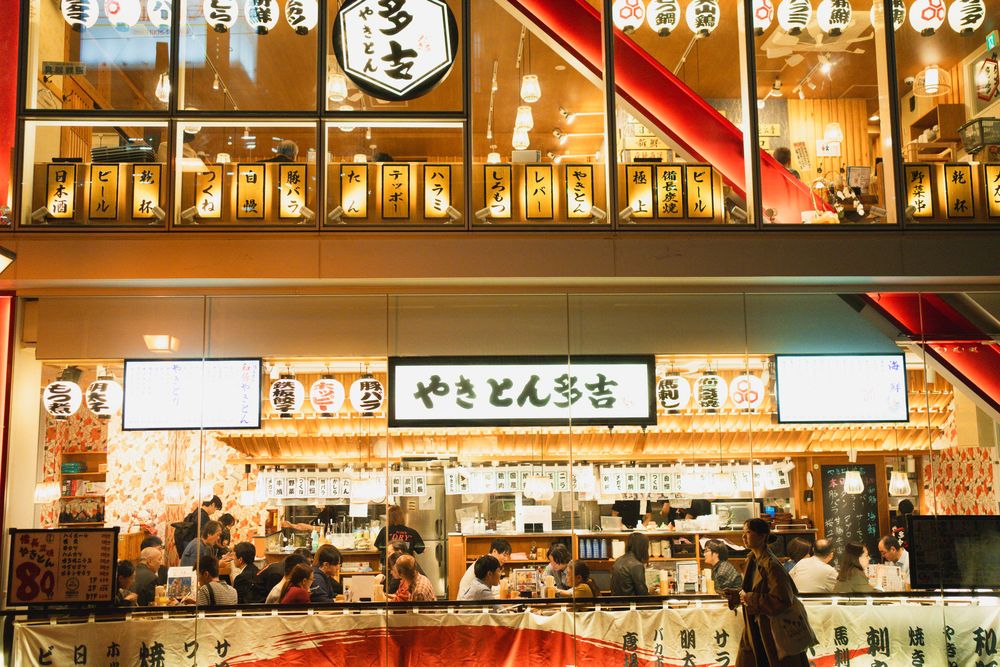 Illuminated Japanese restaurant storefront with traditional lanterns and signage at night.