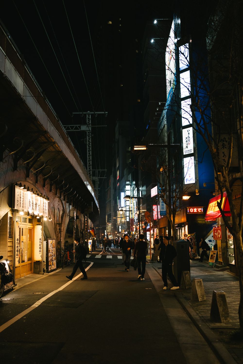 Night street scene in Japan with illuminated storefronts and neon signs casting a warm glow.