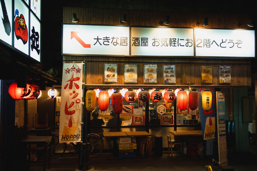 Japanese street with traditional red lanterns and shop signs extending into the distance.