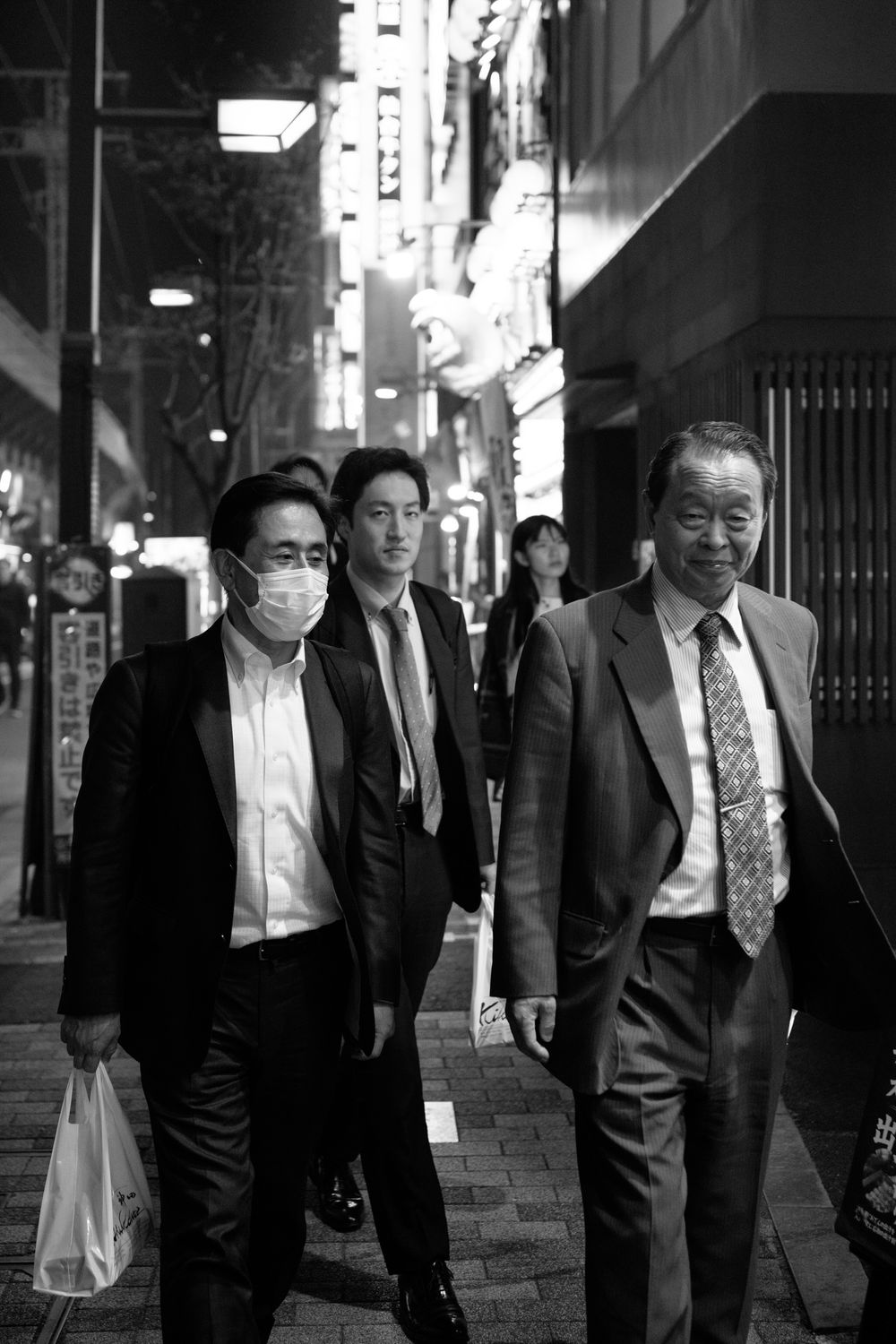 Business professionals walking on a city street at night in Tokyo.