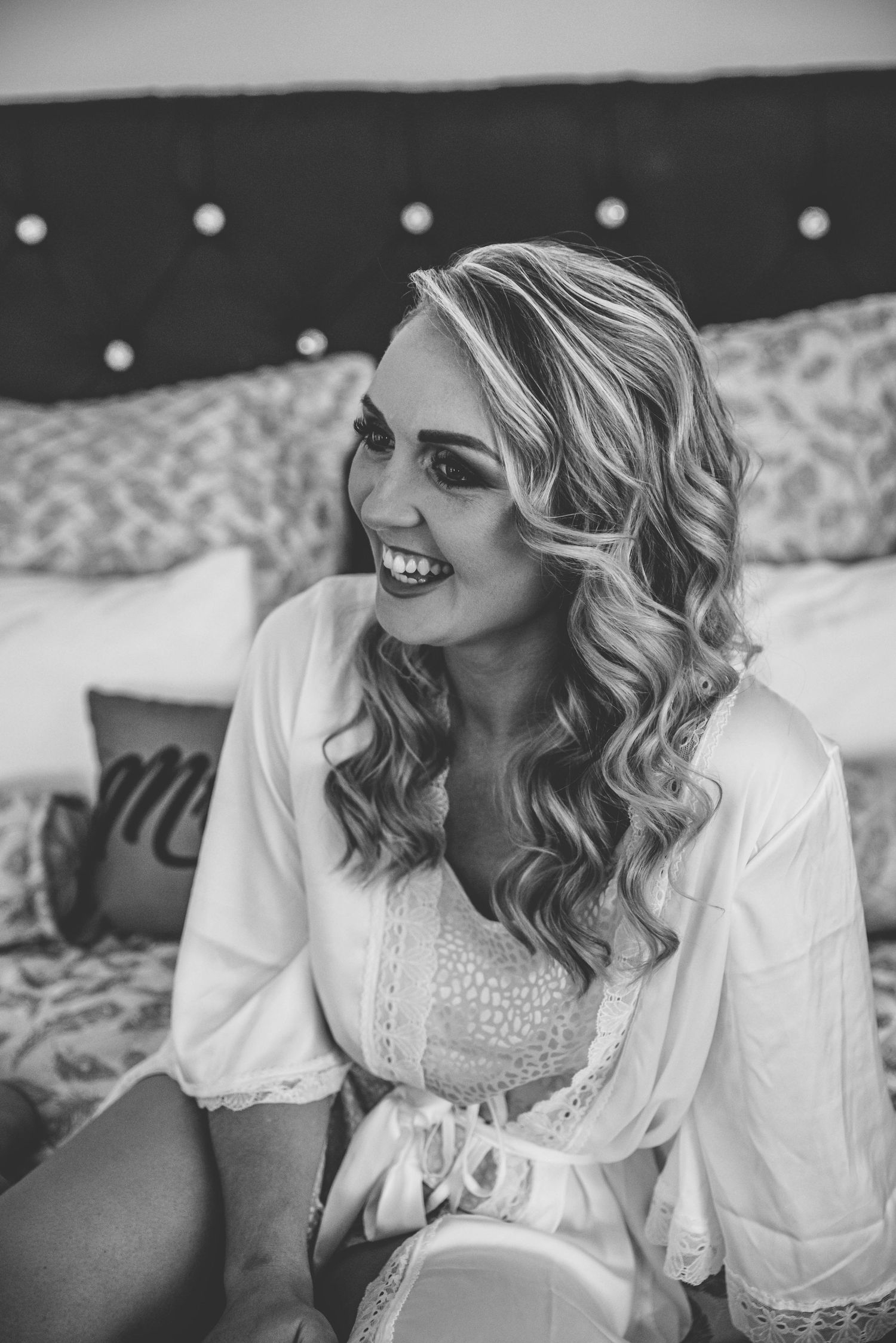 Black and white boudoir photos showing woman in white loungewear smiling at camera.