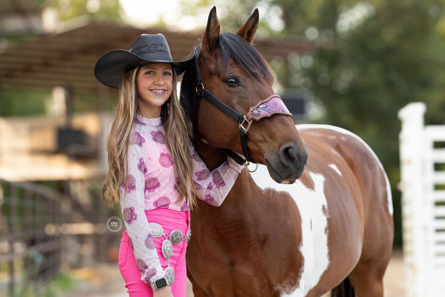 Rider in pink riding outfit leads a chestnut horse with white marking representing grace and equestrian expertise.