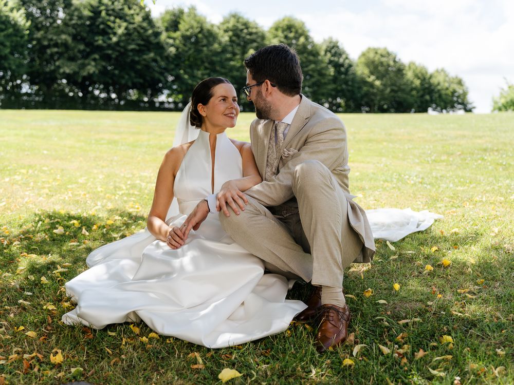 Un couple romantique allongé ensemble sur l'herbe en tenue de mariage lors d'une séance photo en extérieur. Florent Vause