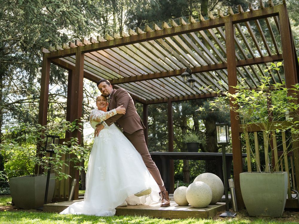 Une scène de mariage en plein air sous une pergola en bois entourée d'une végétation luxuriante. Florent Vause