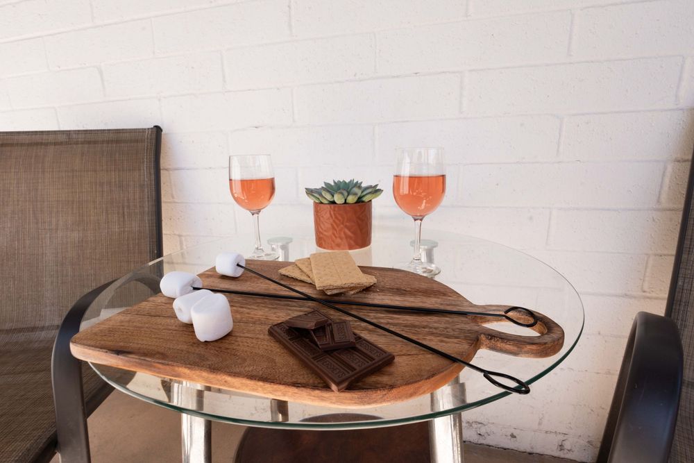 A contemporary furniture set with glass and wood tables, leather chairs, and stylish orange accents in a modern living space.