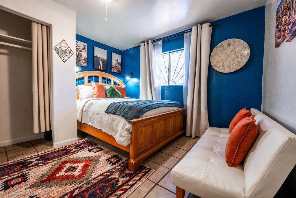 A collage of modern minimalist bedroom interiors with navy blue walls, white bedding, and rustic wooden furniture.