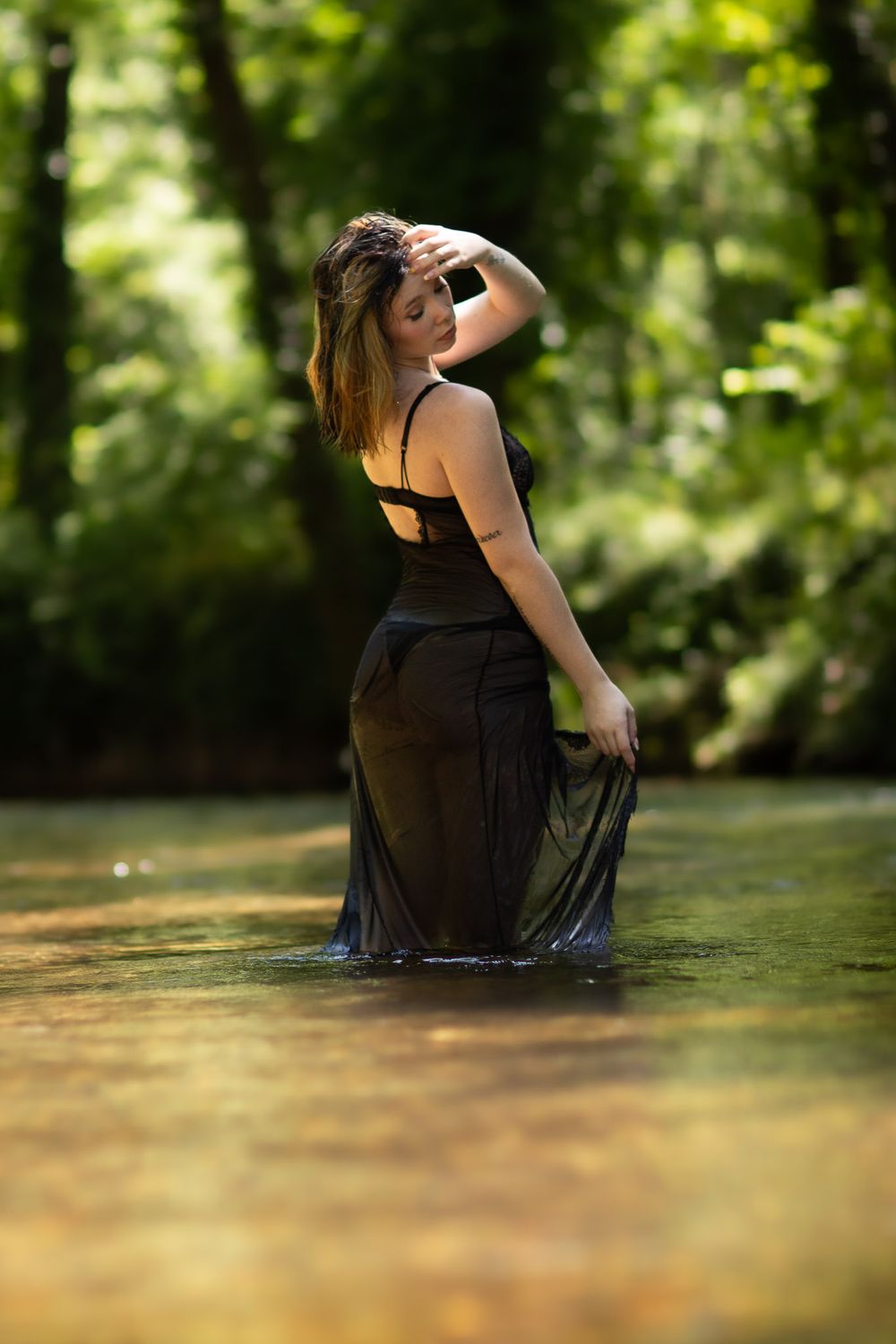 Girl in black dress posing during a creek boudoir photo session in Neosho, Missouri. Captured by Joplin boudoir photographer.