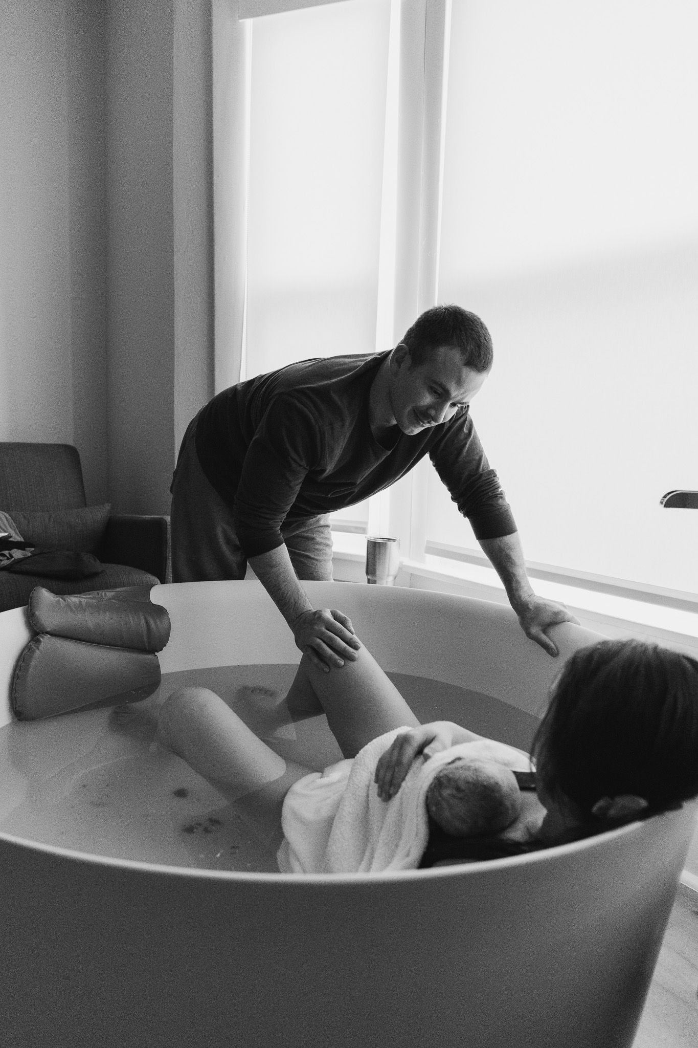Professional birth assistant providing comfort and support during a water birth labor in a serene birthing room setting.