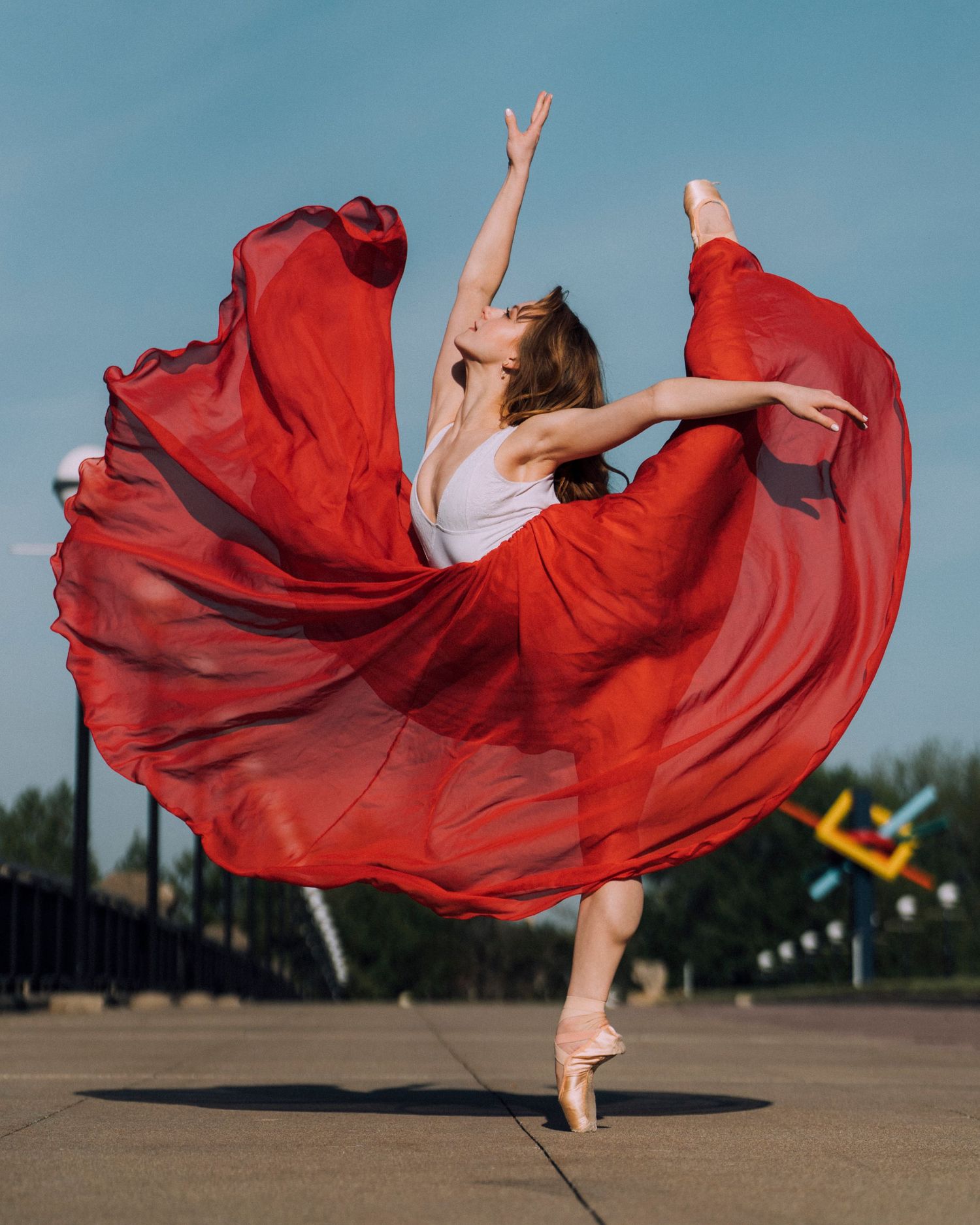 Professional Indianapolis dance photographer capturing a ballerina with red skirt billowing in natural light at White River State Park