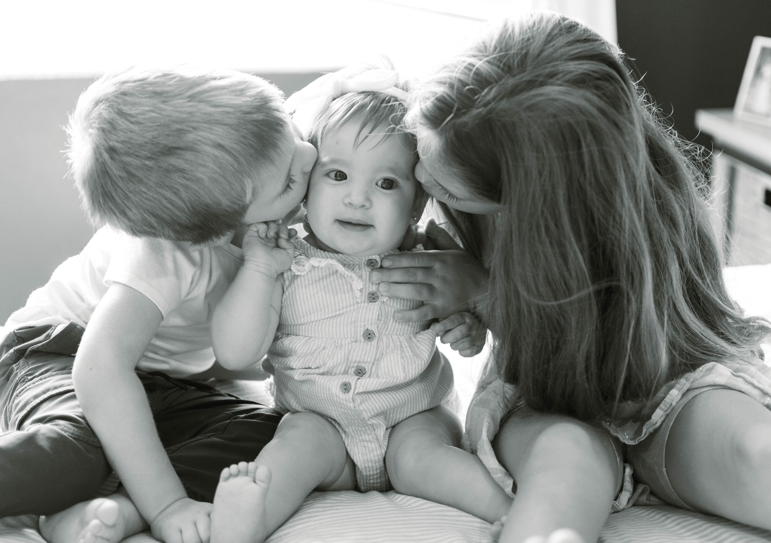 A vintage black and white photograph showing a tender family moment with three people sitting together on a sofa.