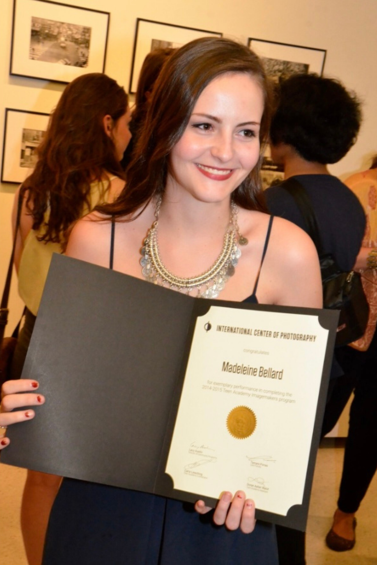 Graduate displays academic certificate in black folder at graduation ceremony.