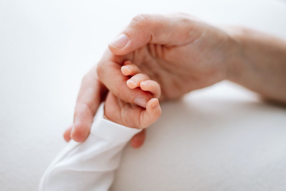 Three hands reach out tenderly and gently touch the center in a delicate show of connection and care.