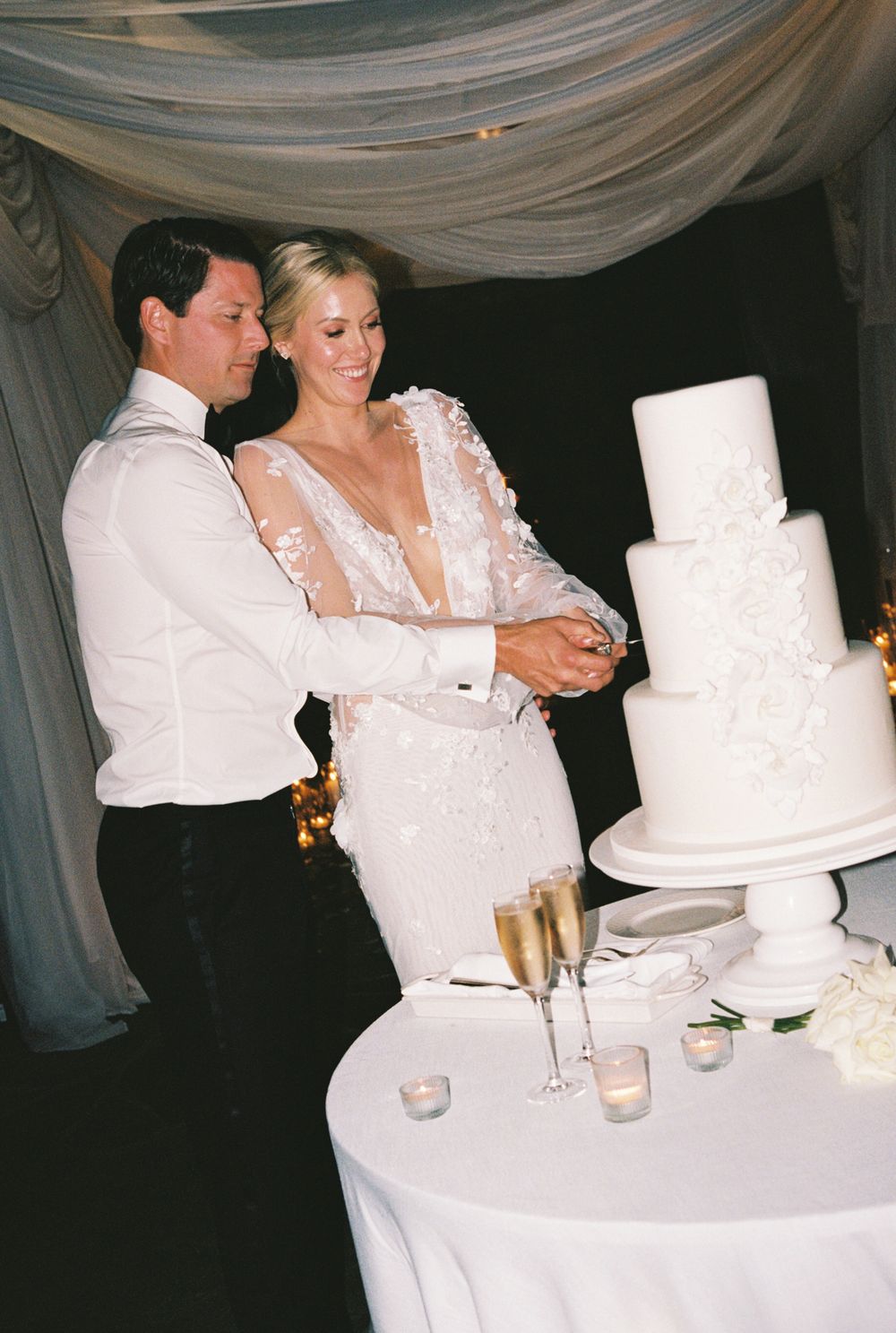 A couple in wedding attire cut and feed each other their white tiered wedding cake during a traditional cake-cutting ceremony. Old Edwards