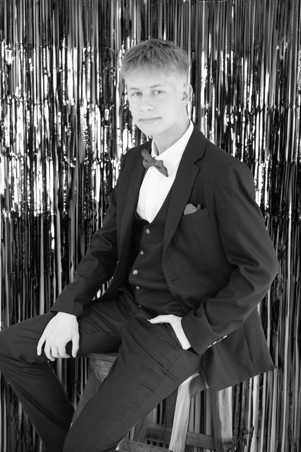 A series of formal portraits with black suit against a metallic tinsel backdrop.