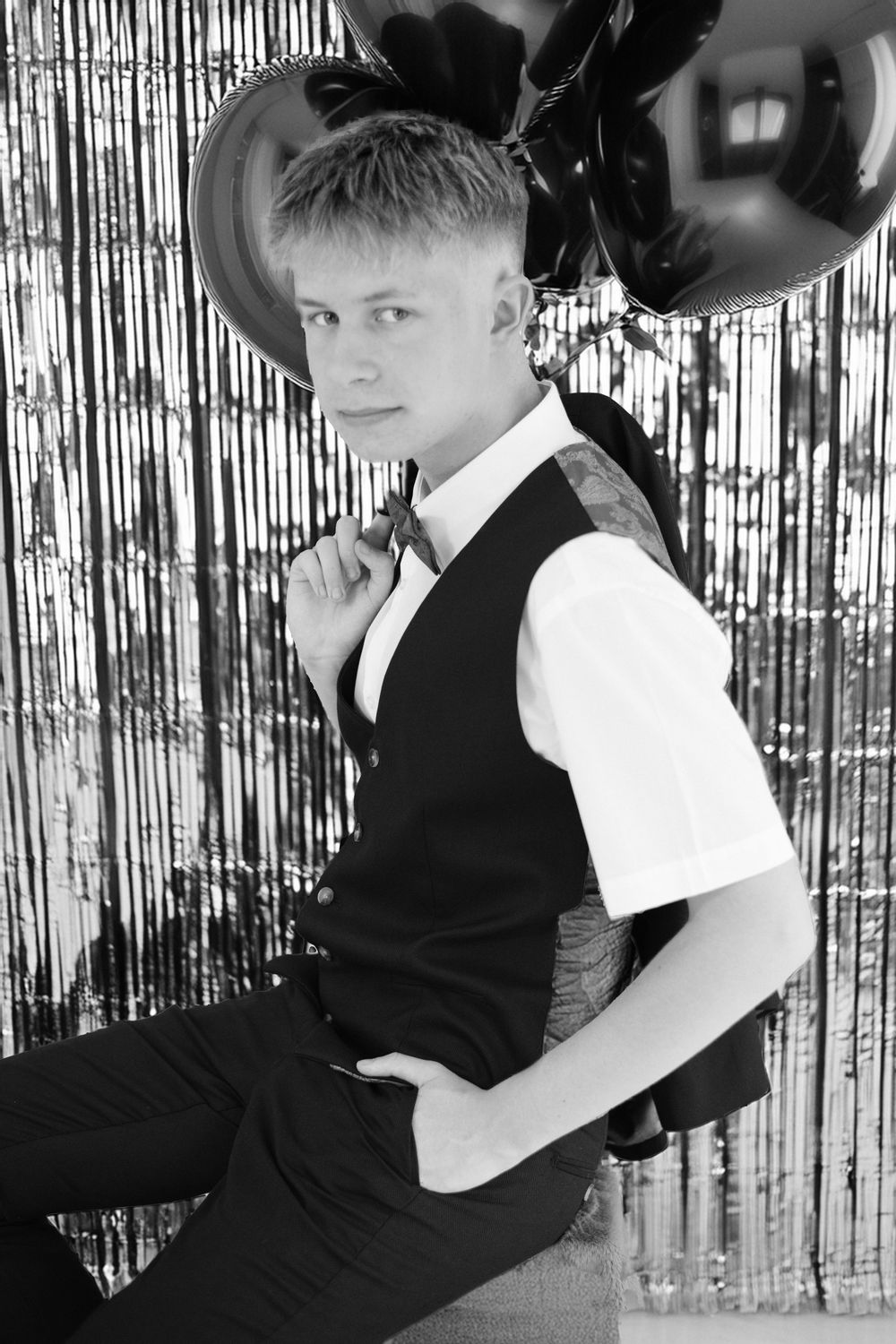 Black and white portrait of a formally dressed student in a vest and white shirt against a sparkly backdrop.