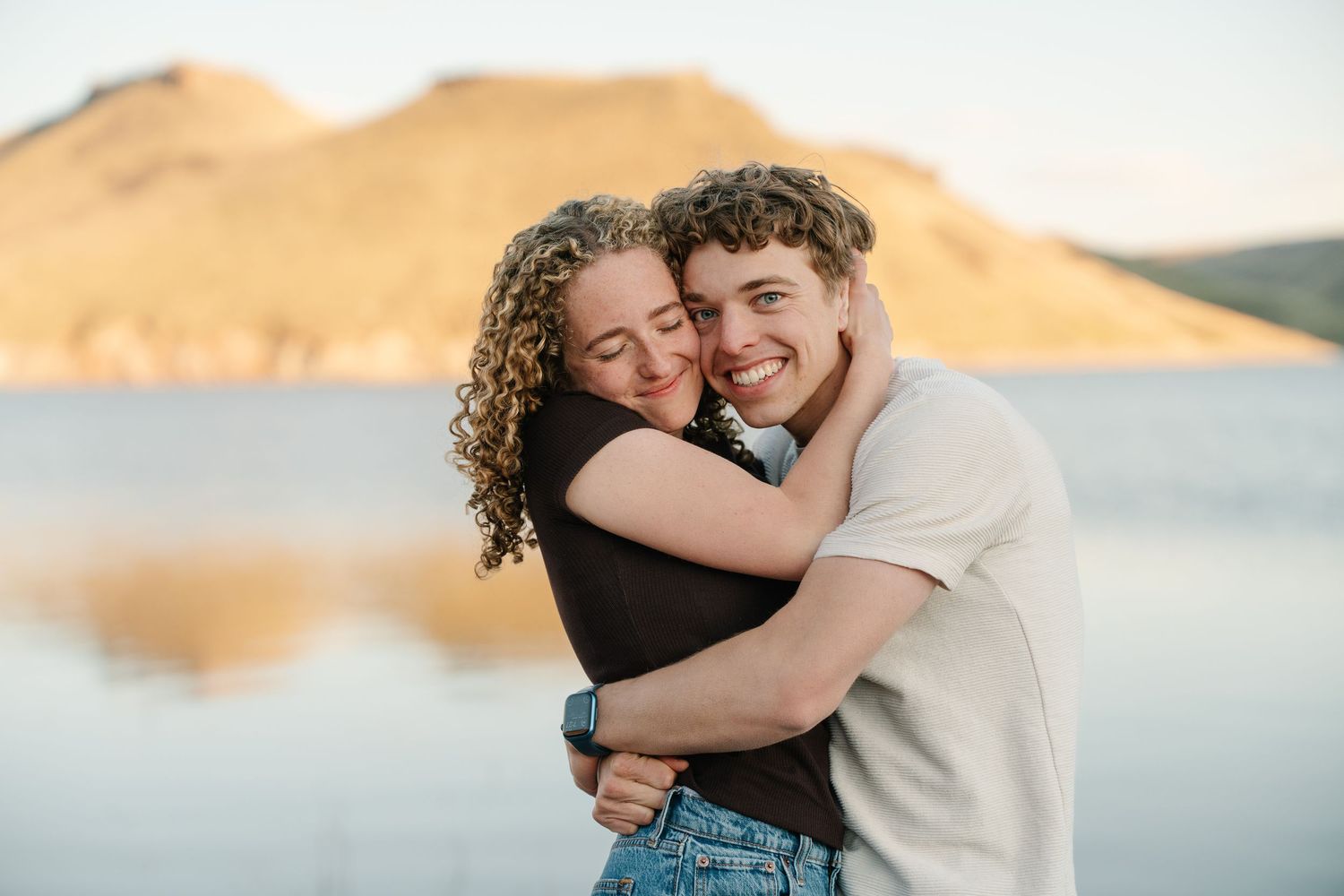 Authentic Des Moines engagement session couple embracing with genuine smiles in natural light
