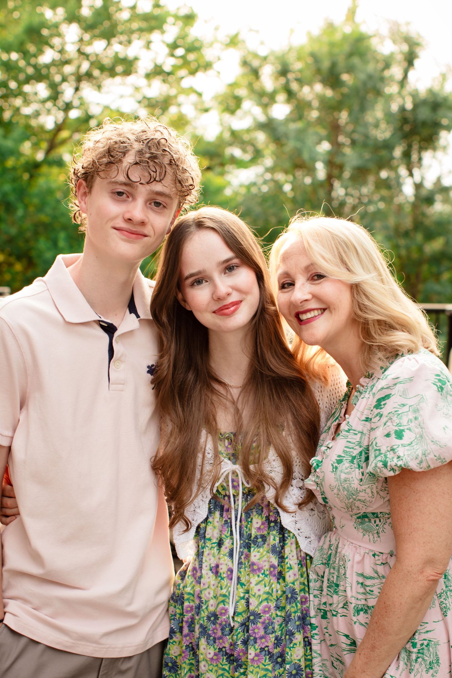 Family wearing coordinating pastel and floral outfits poses together outdoors in natural sunlit setting. Austin Texas