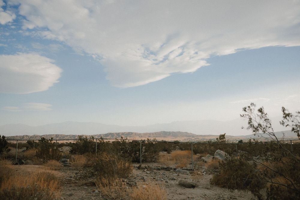 Seven panoramic landscape views of a desert valley with mountains and scattered vegetation under a bright blue sky.