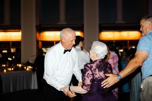 Guests dancing and enjoying themselves at an evening reception with warm lighting and elegant decor.