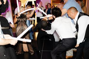 Party guests dancing and having fun with glow sticks on the dance floor at a wedding reception.