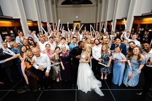 Wedding guests raise their arms in celebration during a lively reception celebration.