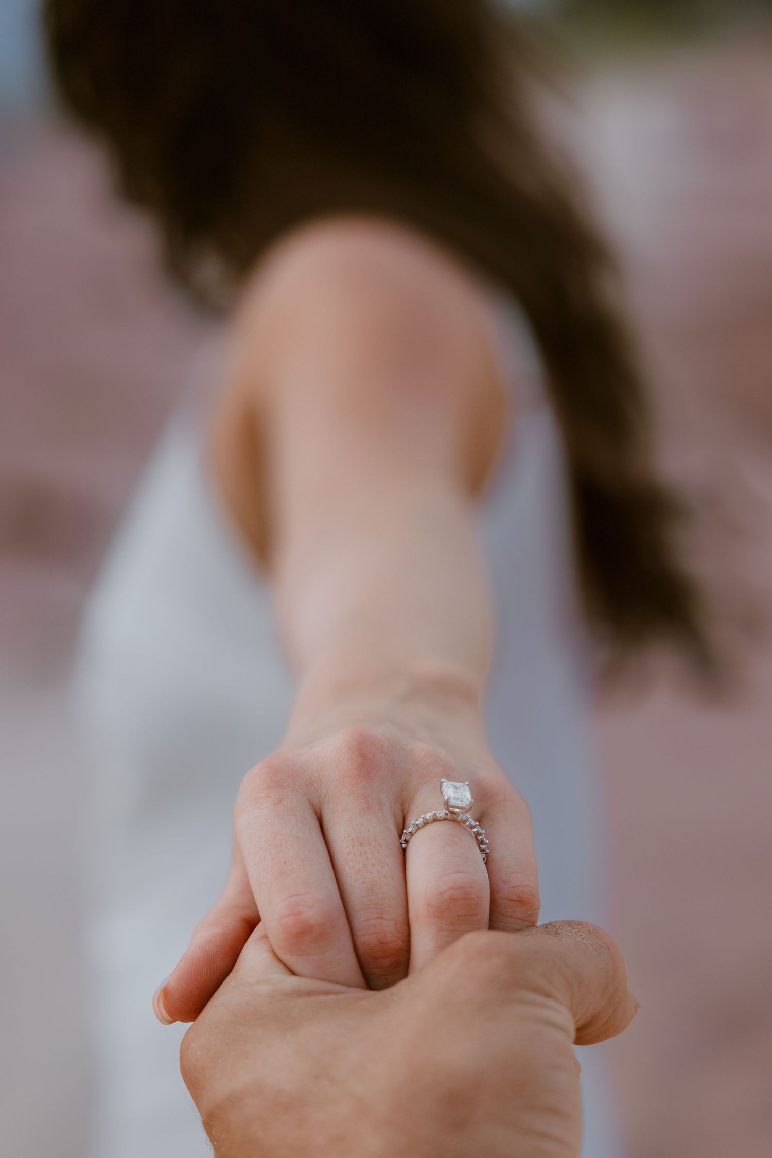 Close up of an engagement ring being shown on a person's hand against a soft blurred background. Metro Detroit Wedding Photographer