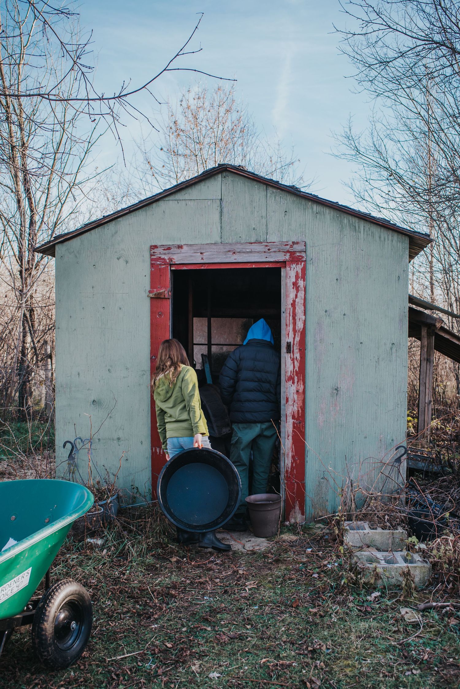 A young girl's back is toward the camera as she looks in a shed.