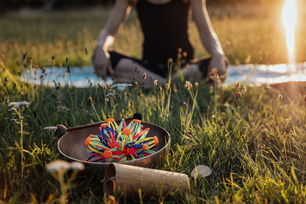 Skateboard with colorful wheels rests in grass during peaceful sunset yoga session.