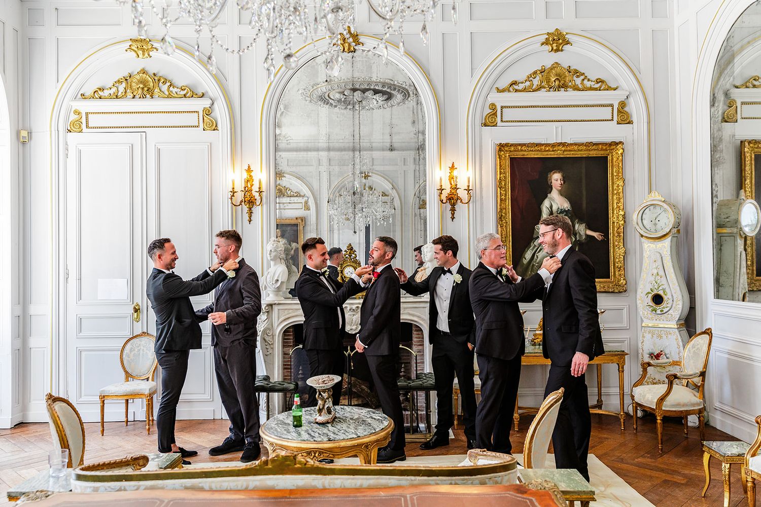 Formal gathering in an ornate white and gold room with classical architectural details.