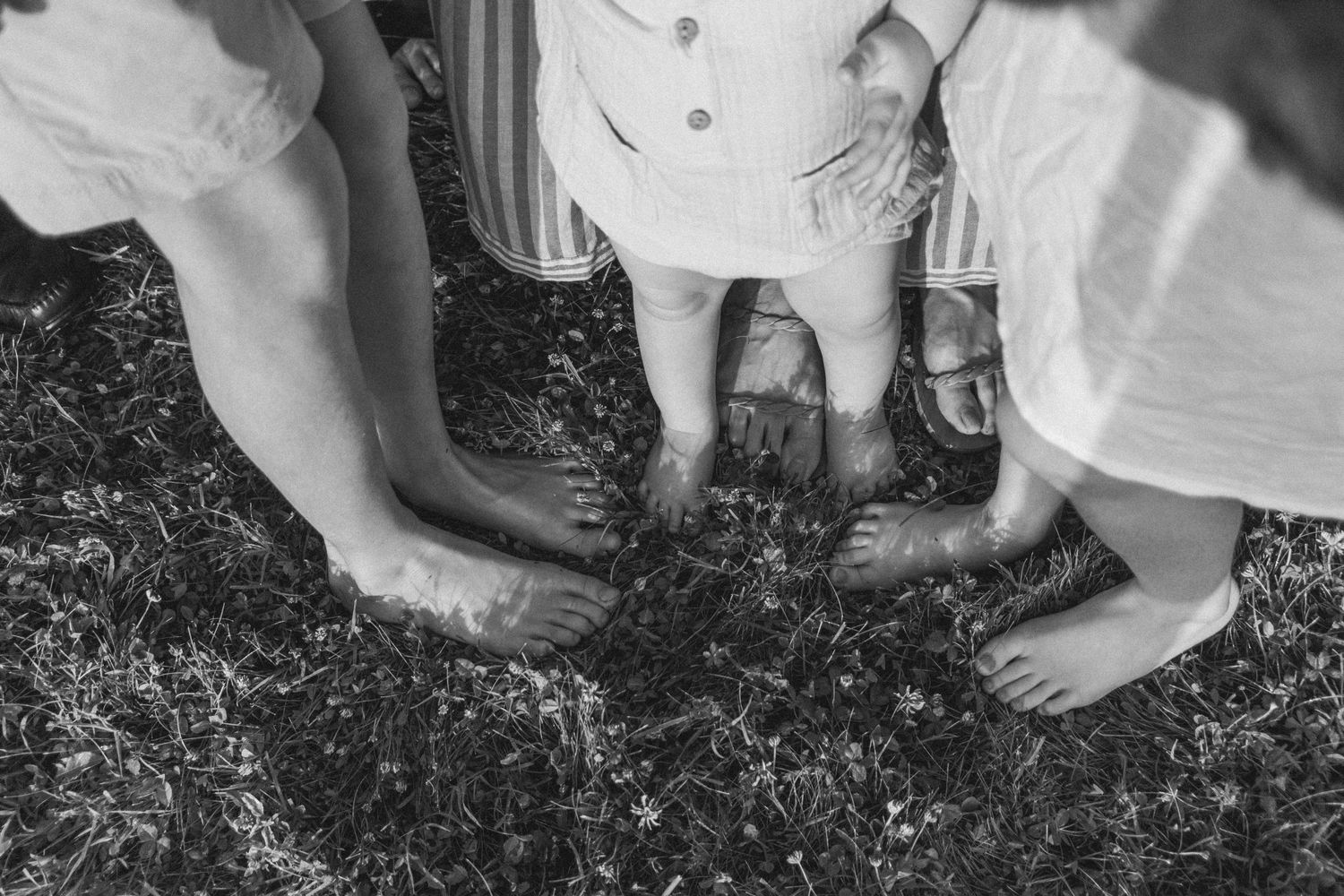 Crianças brincam com os pés descalços na grama em sessão de fotos na Toscana