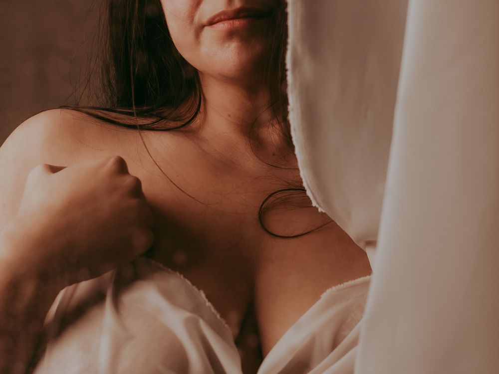 Boudoir fotografie van een vrouw met een witte doek gedrapeerd voor haar lichaam