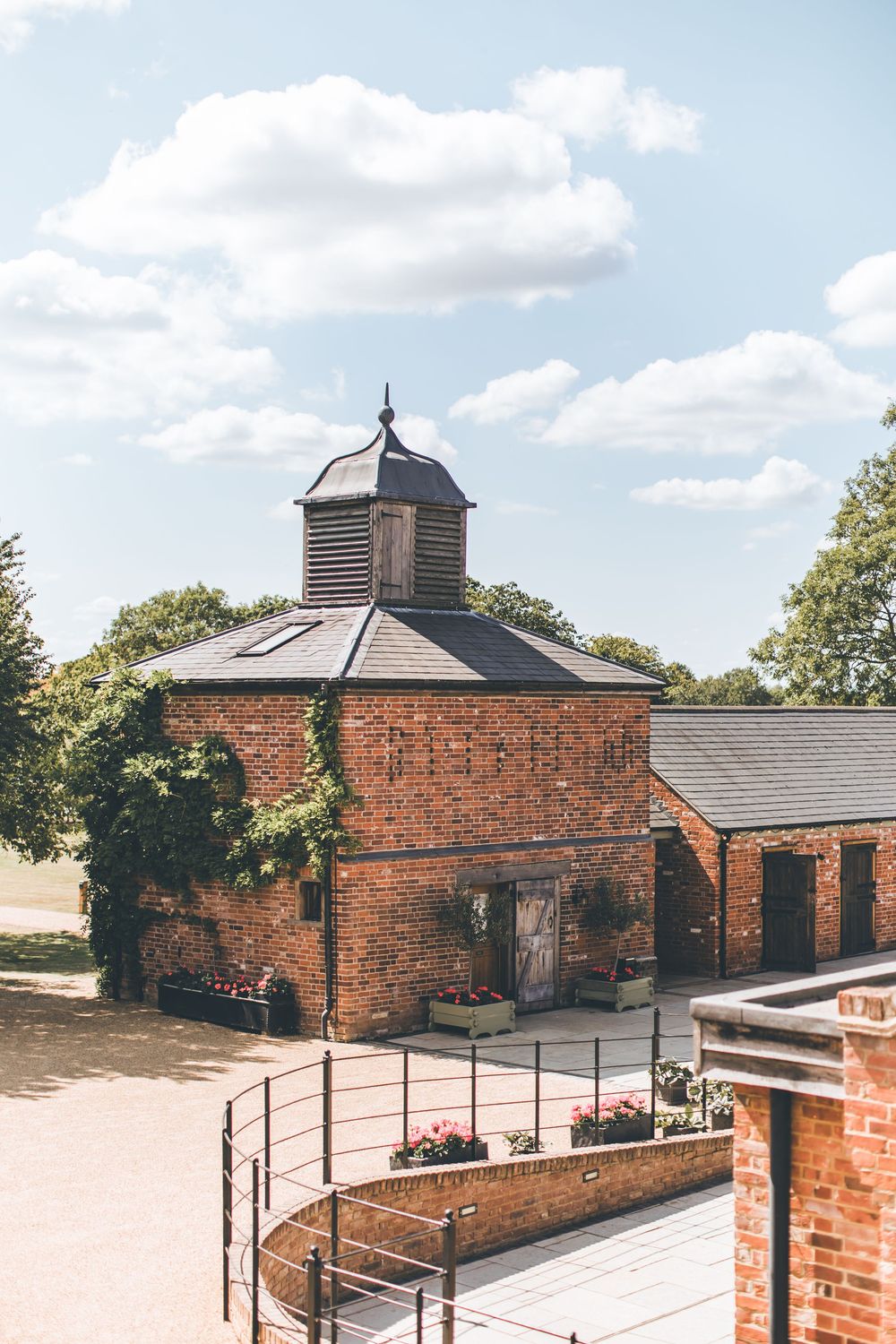 Historic red brick building with cupola under blue sky at wedding venue.